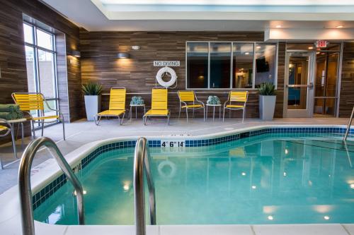 Fairfield Inn & Suites by Marriott Lincoln Southeast في لينكولن: حمام سباحة في الفندق مع كراسي وطاولات صفراء