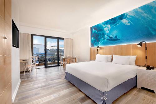 Protea Hotel Fire & Ice! by Marriott Durban Umhlanga Ridge في ديربان: غرفة فندقية بسرير كبير وطاولة