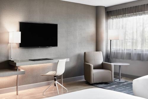 a hotel room with a desk and a chair and a television at AC Hotel by Marriott Pleasanton in Pleasanton