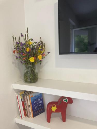 a shelf with a vase of flowers and books at PLACIDO RIVER HOUSE APARTAMENTO in Ponte da Barca