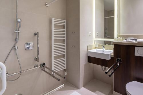 a bathroom with a sink and a shower and a toilet at Courtyard by Marriott Sarajevo in Sarajevo