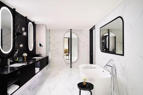 a bathroom with two sinks and a tub and mirrors at Le Meridien Seoul Myeongdong in Seoul