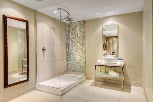 a bathroom with a shower and a sink and a mirror at Protea Hotel by Marriott Transit O.R. Tambo Airport in Kempton Park