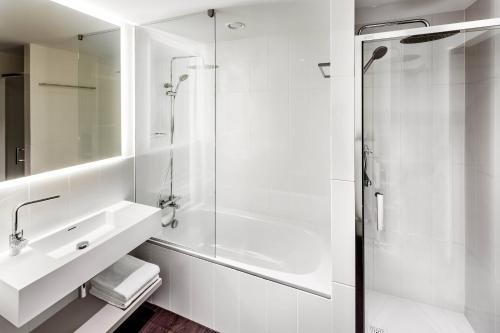 a white bathroom with a sink and a shower at Courtyard by Marriott Prague Airport in Prague