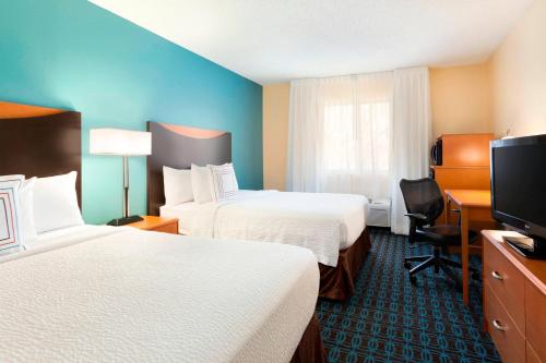 a hotel room with two beds and a flat screen tv at Fairfield Inn & Suites Midland in Midland
