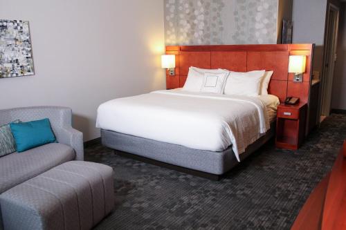 une chambre d'hôtel avec un lit et un canapé dans l'établissement Courtyard by Marriott Owensboro, à Owensboro
