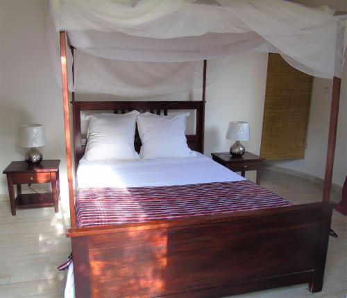 a bedroom with a large wooden bed with two night stands at WouroBa in Mbodiène