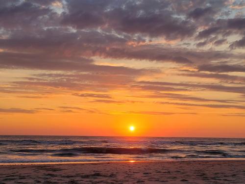 a sunset on the beach with the sun setting at Tiny Villa de Haas met Infraroodsauna in Egmond aan Zee