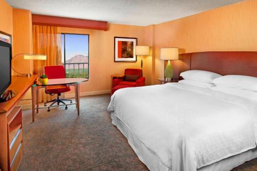 um quarto de hotel com uma cama, uma secretária e uma televisão em Sheraton Albuquerque Airport Hotel em Albuquerque