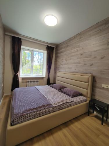 a bedroom with a bed with a wooden wall at Квартира в районе 5-ой фонтана in Odesa