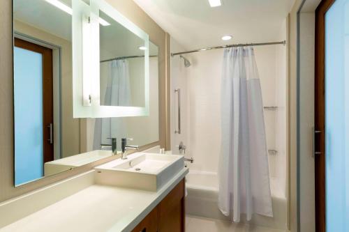 a bathroom with a sink and a mirror and a shower at SpringHill Suites Orange Beach at The Wharf in Orange Beach