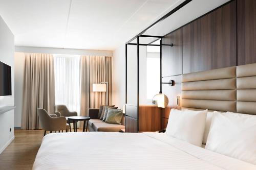 a hotel room with a large bed and a chair at AC Hotel by Marriott Stockholm Ulriksdal in Solna