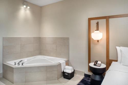 a bathroom with a bath tub next to a bed at Fairfield Inn by Marriott Toronto Oakville in Oakville