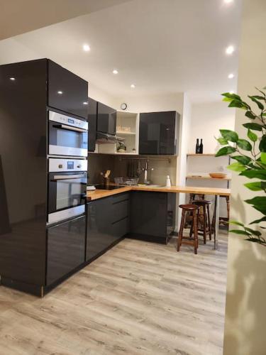 une cuisine avec des armoires noires et une table avec des chaises dans l'établissement Appartement avec baignoire - Hautvillers, à Hautvillers