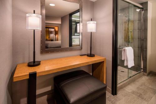 a bathroom with a vanity with a mirror and a stool at Oakland Marriott City Center in Oakland