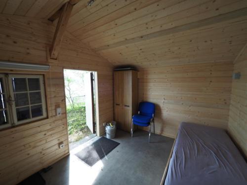 1 dormitorio en una cabaña de madera con una silla azul en Häuschen direkt am See, en Reichenau
