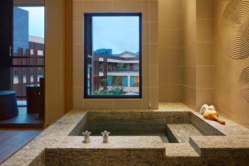 uma casa de banho com uma grande banheira e uma janela em The Westin Yilan Resort em Yuanshan