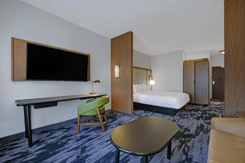 a hotel room with a bed and a desk with a tv at Fairfield Inn & Suites by Marriott Milwaukee Brookfield in Brookfield