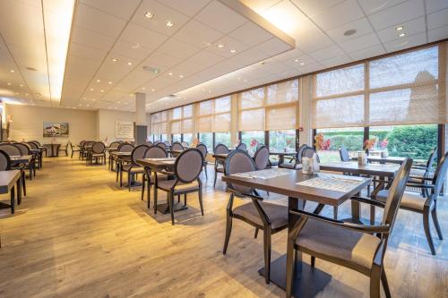a dining room with tables and chairs and windows at Fletcher Hotel Restaurant De Geulvallei in Valkenburg