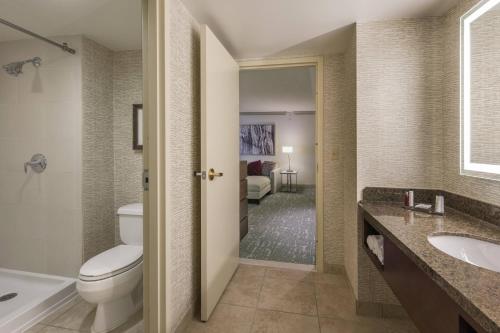 a bathroom with a toilet and a tub and a sink at Denver Airport Marriott at Gateway Park in Aurora