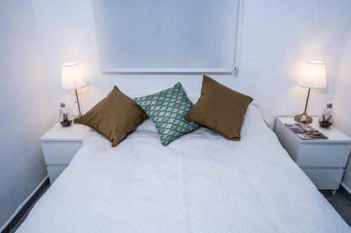 um quarto com uma cama branca com almofadas e 2 candeeiros em Sea View Boutique Apartment em Eilat