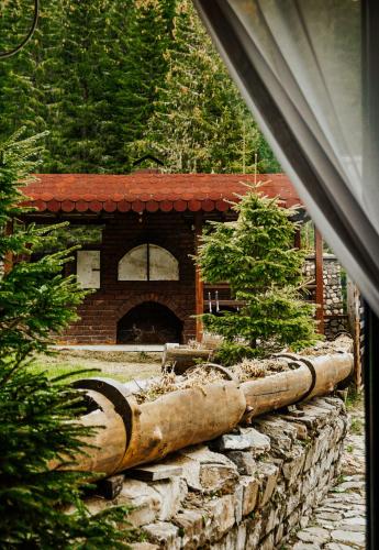 a garden with a stone wall and a building at Cabana Laptici - statiunea Pestera-Padina, Bucegi in Sinaia