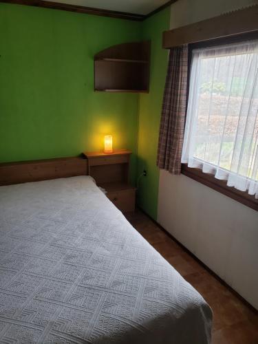 een groene slaapkamer met een bed en een raam bij Chalet 176 in Durbuy
