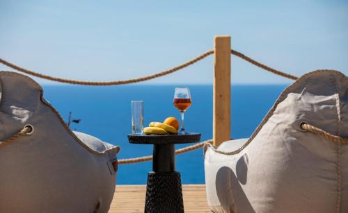 a glass of wine and fruit on a table on a deck at Eunoia Porto Katsiki in Áyios Nikólaos Nirás