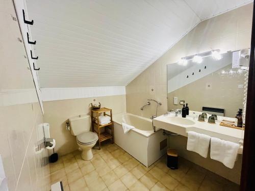 a bathroom with a sink and a tub and a toilet at Hôtel les Chaumettes in Savines