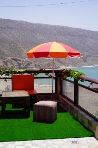 a patio with a table and an umbrella and a chair at Auberge guest house imsouane n°5 in Imsouane