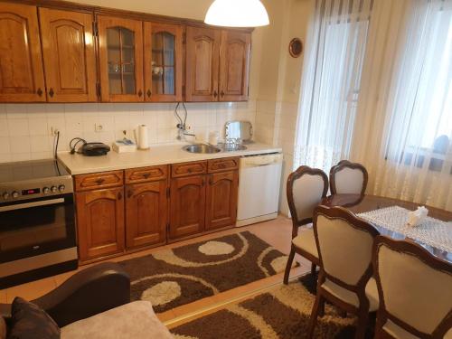 eine Küche mit Holzschränken und einem Tisch mit Stühlen in der Unterkunft H Apartament in Pristina