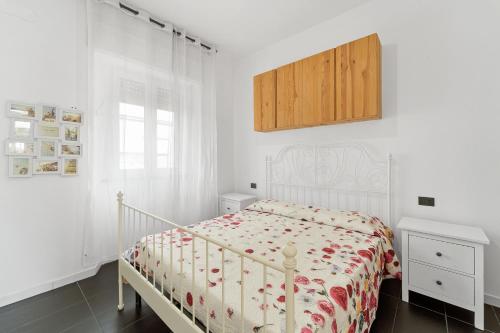 a white bedroom with a bed and a wooden cabinet at Nonna Gina in Arbus