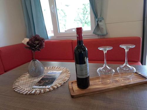 a bottle of wine and two wine glasses on a table at Borić Mobile Homes in Bijela Uvala and Zelena Laguna in Poreč