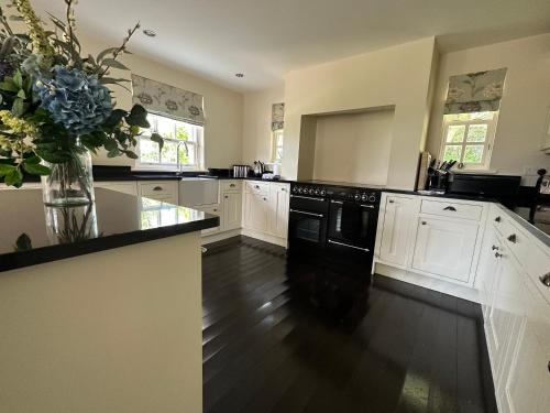una cocina con electrodomésticos negros y un jarrón de flores en Ann's Hill en Cockermouth