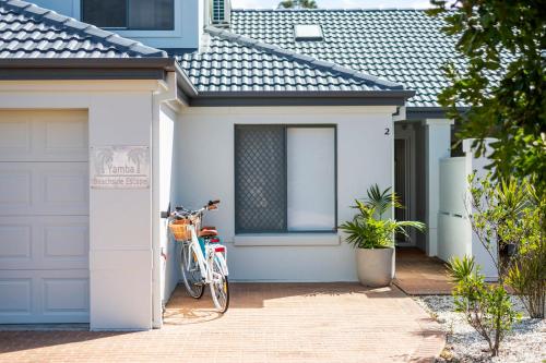 a bike parked in front of a white garage at Yamba Beachside Escape - oceanstays in Yamba