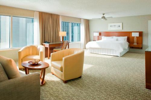 ピッツバーグにあるThe Westin Pittsburghのベッドと椅子が備わる広いホテルルームです。