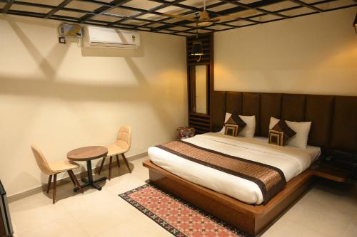 a bedroom with a bed and a table and chairs at Hotel Grand Kailash,Kotdwara in Kotdwāra