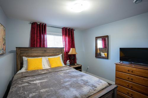 Un dormitorio con una cama con almohadas amarillas y un televisor. en Two Bedroom Apartment Near St John's Airport, en St. John's