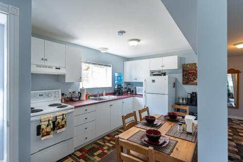 cocina con armarios blancos, mesa y sillas en Two Bedroom Apartment Near St John's Airport, en St. John's