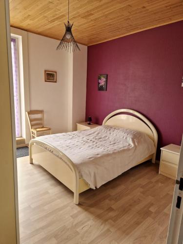 une chambre avec un lit et un mur violet dans l'établissement Gîte AUDREY, à Saint-Martial-de-Valette
