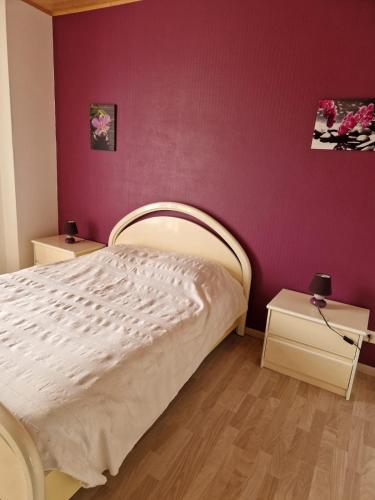 une chambre avec un lit et un mur violet dans l'établissement Gîte AUDREY, à Saint-Martial-de-Valette