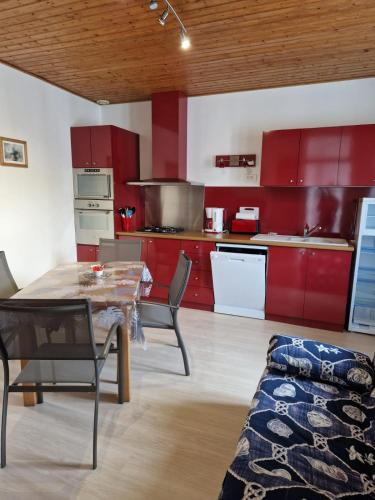 une cuisine avec des armoires rouges et une table et des chaises dans l'établissement Gîte AUDREY, à Saint-Martial-de-Valette
