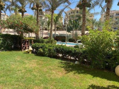 a yard with a swimming pool and palm trees at Chalet in Stella Marina, El Alamein in El Alamein