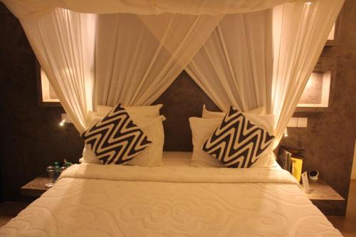 a bedroom with a canopy bed with white sheets and pillows at Villa Le Petit Paradis Saly Boutique Hotel in Ngaparou