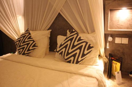 a bed with black and white pillows on it at Villa Le Petit Paradis Saly Boutique Hotel in Ngaparou