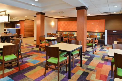 Fairfield Inn & Suites Cleveland Avon في Avon: غرفة طعام مع طاولات وكراسي على سجادة ملونة