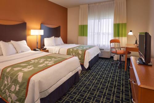 Fairfield Inn and Suites by Marriott Laramie في لارامي: غرفة فندقية بسريرين ومكتب وتلفزيون