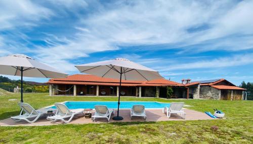 a pool with chairs and umbrellas and a house at Quinta do Mirante in Celorico de Basto