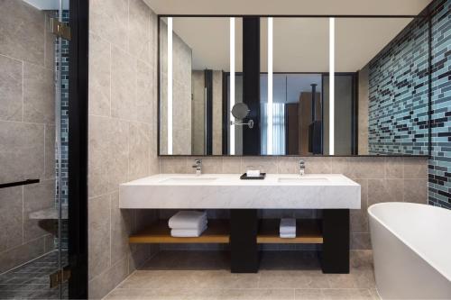 een badkamer met een wastafel, een bad en een spiegel bij Fairfield by Marriott Shanghai Hongqiao NECC in Shanghai