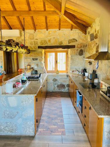 a large kitchen with stone walls and wooden ceilings at Quinta do Mirante in Celorico de Basto